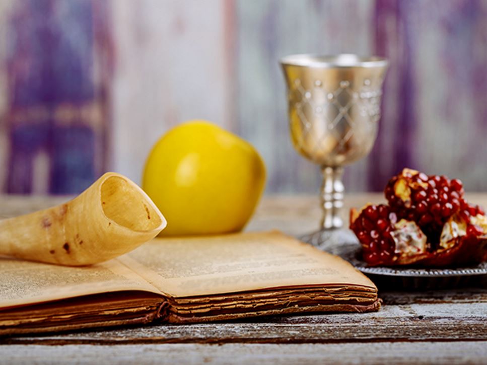 Apple and pomegranate on wooden table over bokeh background to show Yom Kippur traditions