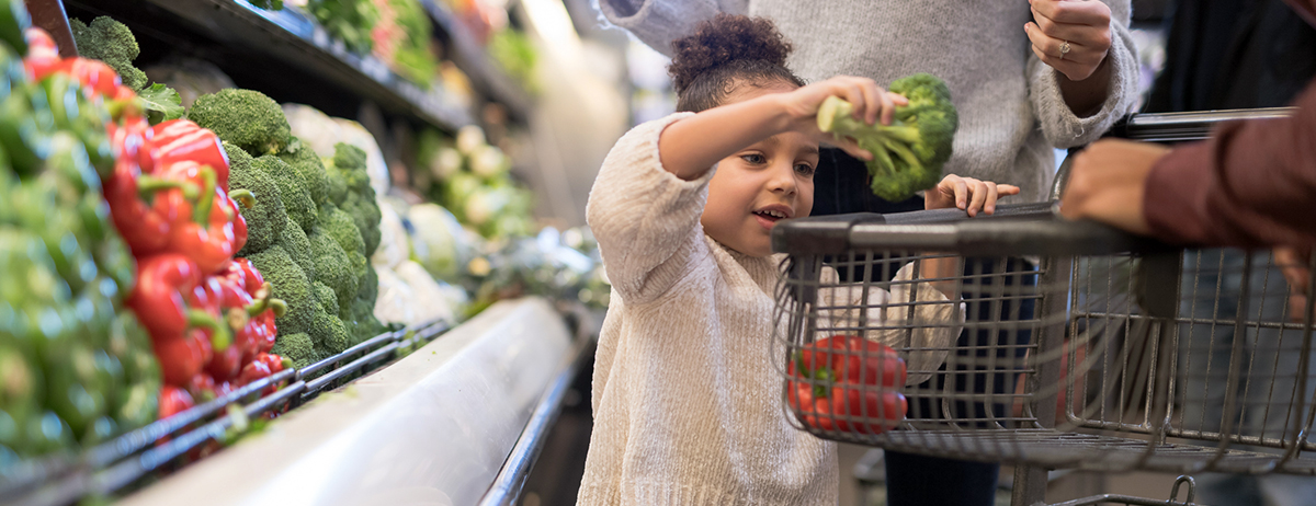 young girl choosing fresh vegetables at the supermarket